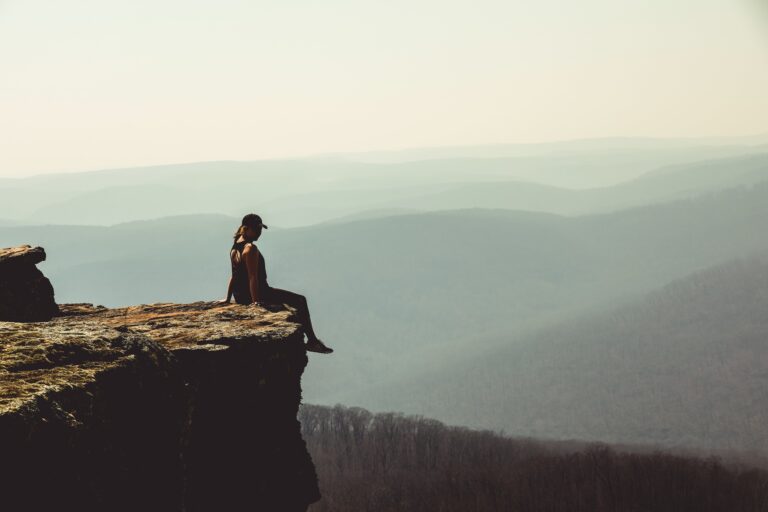 Woman sitting on the edge of a cliff, admiring the nature